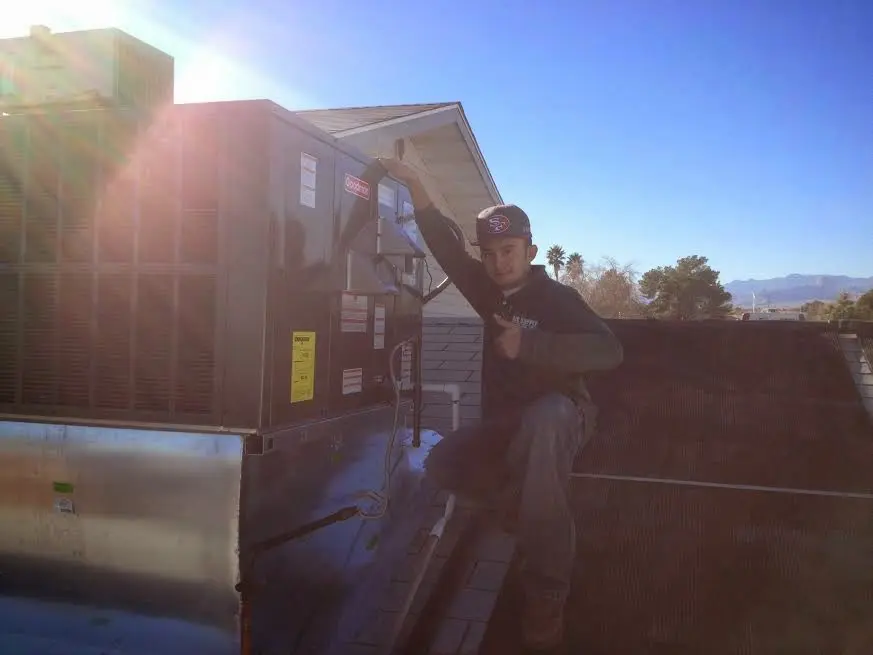 HVAC technician performing AC Tune-Up on a rooftop unit in Plymouth